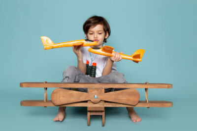 front view little boy playing with toy planes blue floor